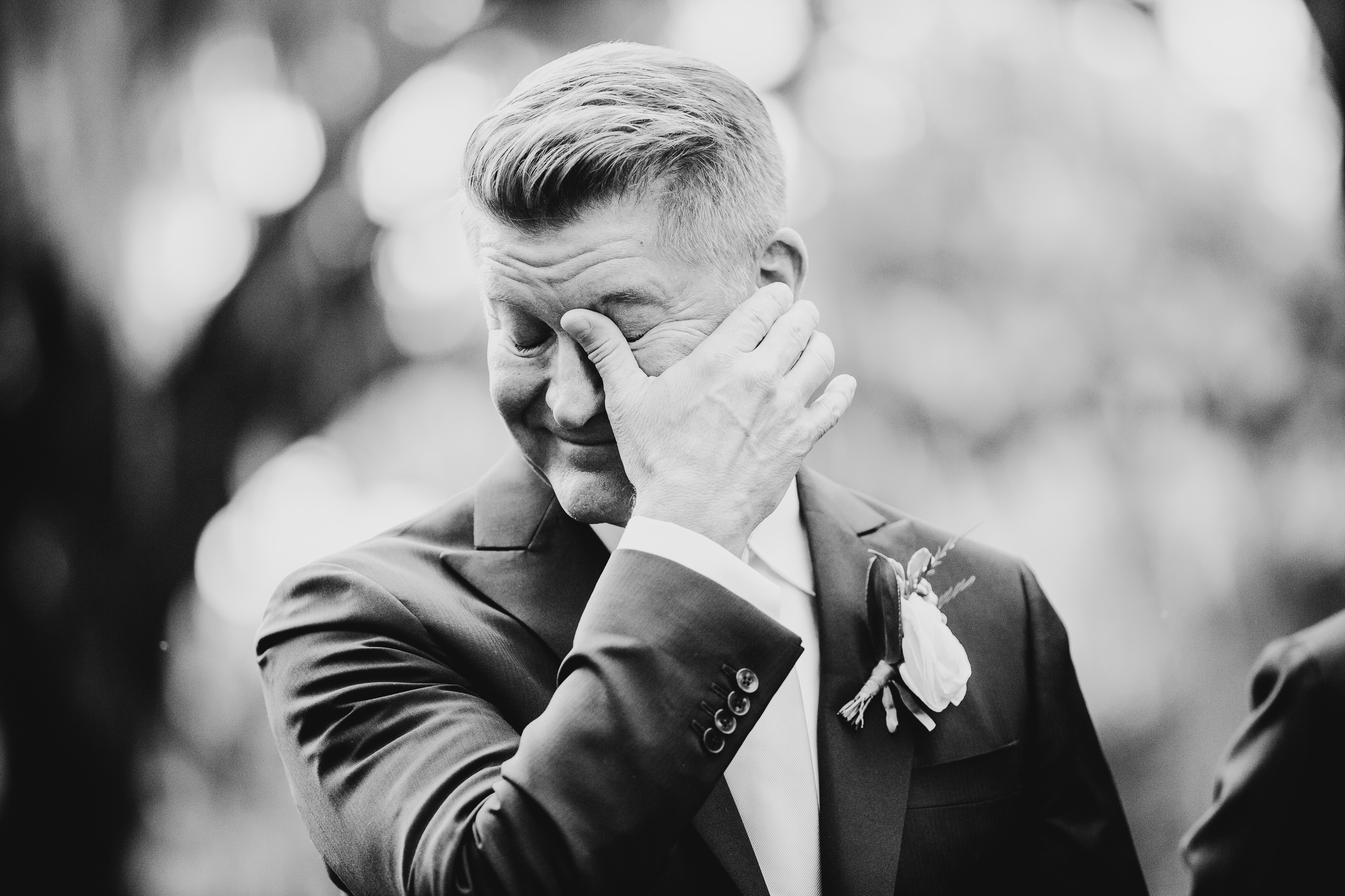 Groom wiping a tear away from his eye as he sees his bride walk down the aisle