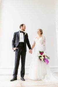 bride and groom portraits in front of white wall