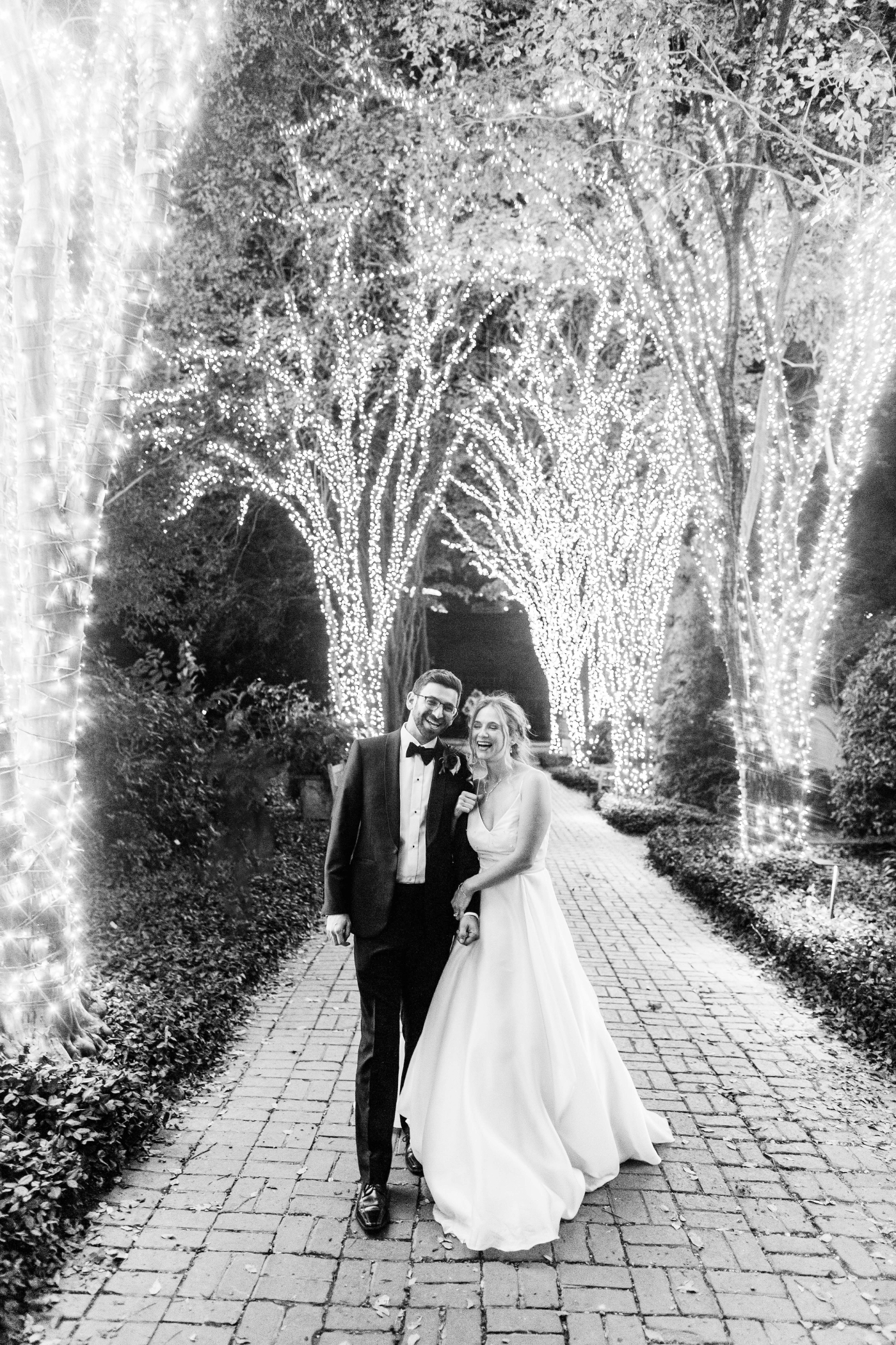 bride and groom outside with tree lights