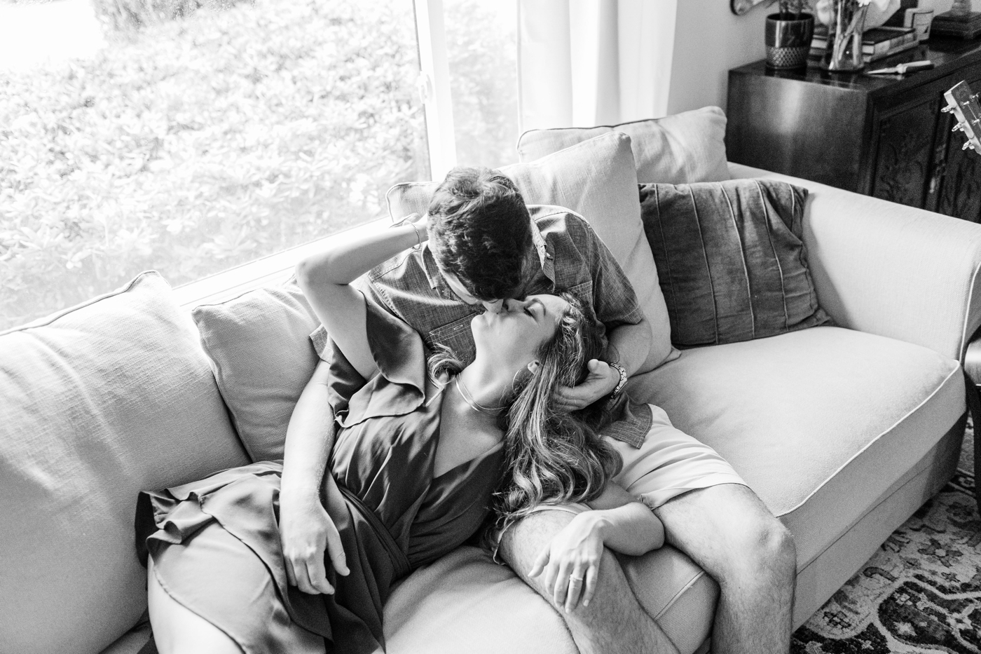 Couple kissing on their couch for their at-home engagement session