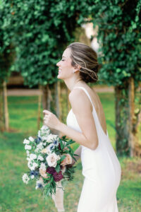 A bride laughing while holding a bouquet.