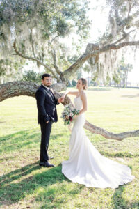 A bride and groom standing by an oak tree.