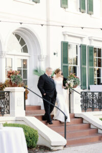 A bride walking down steps with her father.