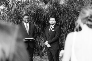 A groom standing with an officiant waiting for his bride.