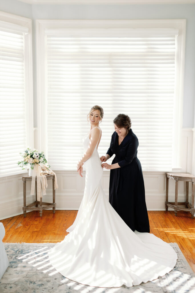 A mother helping her daughter into her wedding dress.