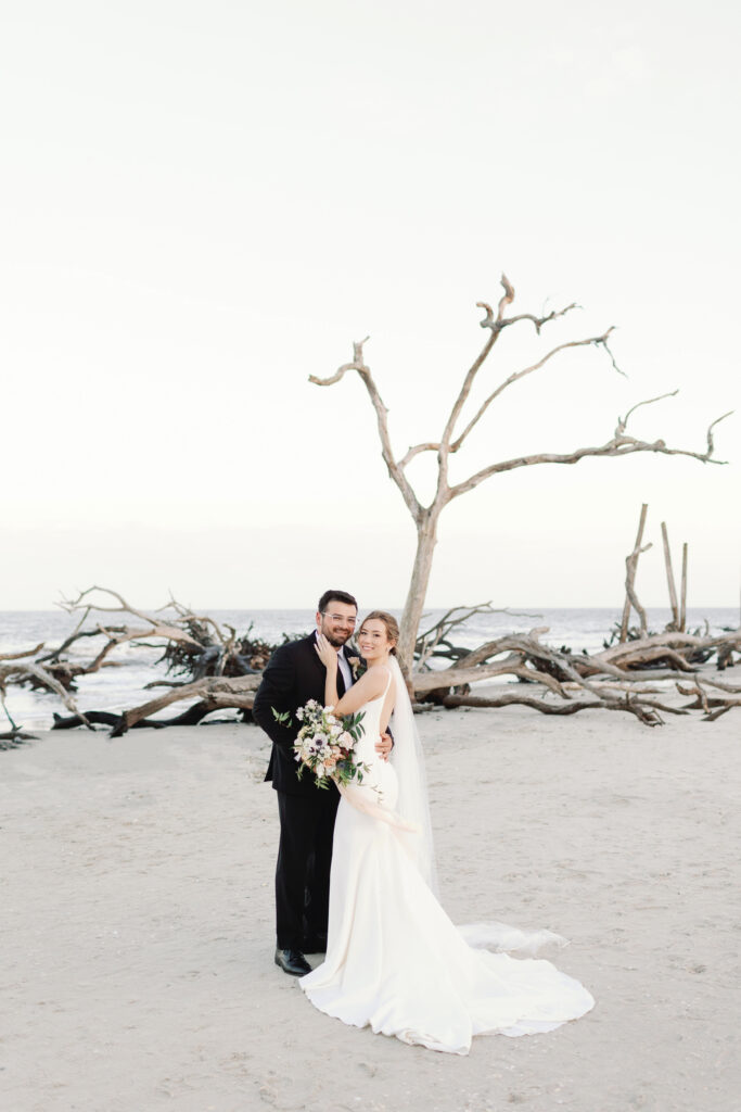 A bride and groom hold one another on the beach.