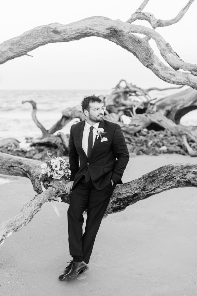 A groom relaxes on a piece of driftwood.