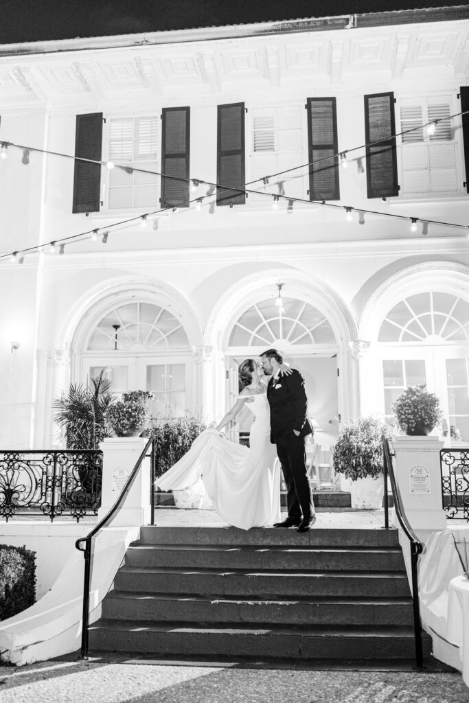 A bride and groom kiss at the top of stairs.