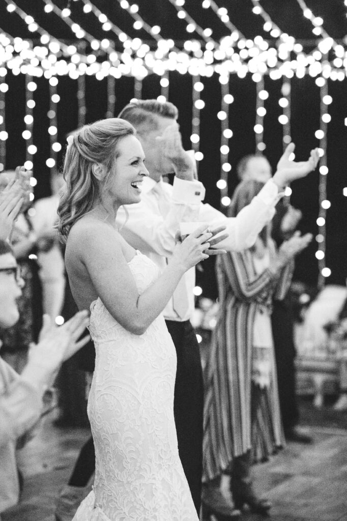 A bride and groom cheers a band on stage.