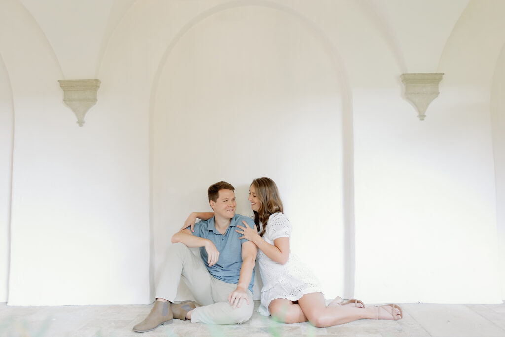Sea Island Engagement couple sit against a wall