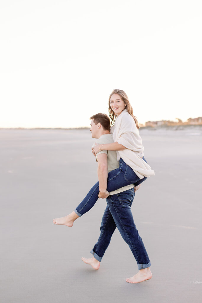 A young man gives his fiance a piggy back ride. 