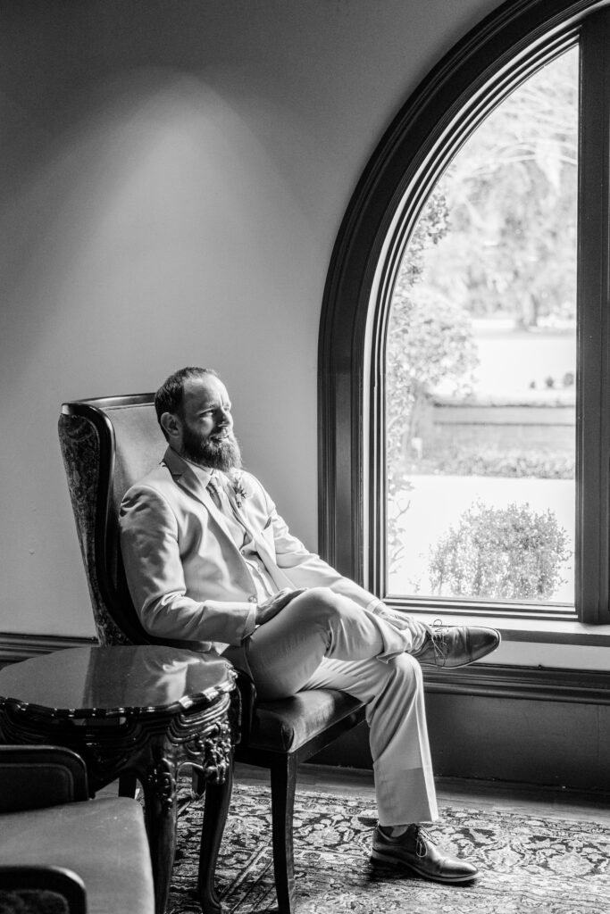 A groom sitting by a window. 