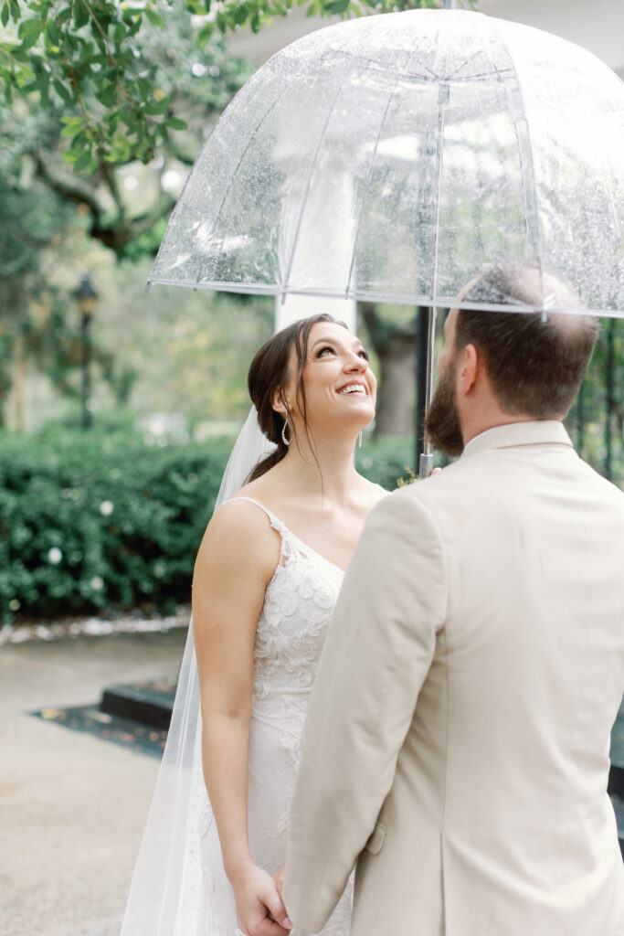 A bride and groom share an umbrella. 