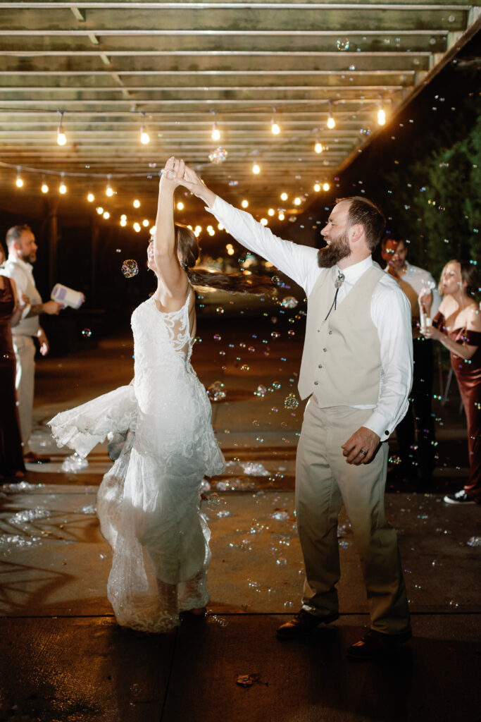 A groom spins his bride during a bubble exit. 